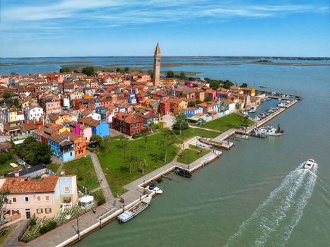 Aerial view of the vibrant Burano island a kaleidoscope of colorful houses under a clear sky with the iconic leaning bell tower of San Martino Venice Veneto Italy. Aerial view of the vibrant Burano island a kaleidoscope of colorful houses under a clear sky with the iconic leaning bell tower of San Martino Venice Veneto Italy.