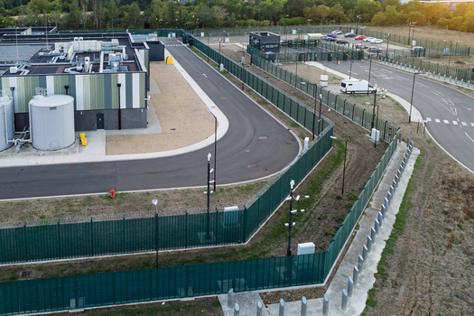 Aerial view of a data center with security fencing surveillance cameras and industrial infrastructure in the United Kingdom. Aerial view of a data center with security fencing surveillance cameras and industrial infrastructure in the United Kingdom.