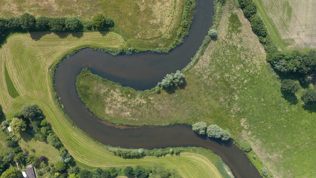 Aerial view of the meandering Berkel river flowing through lush green meadows and agricultural fields in Almen Gelderland Netherlands. Aerial view of the meandering Berkel river flowing through lush green meadows and agricultural fields in Almen Gelderland Netherlands.