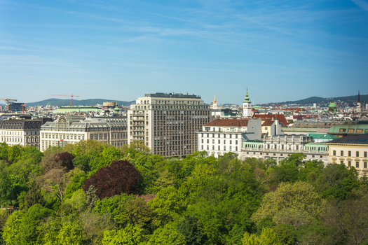 Aerial view of historic and modern buildings rising above the lush green trees of Stadtpark under a clear blue sky in Vienna Vienna Austria. Aerial view of historic and modern buildings rising above the lush green trees of Stadtpark under a clear blue sky in Vienna Vienna Austria.