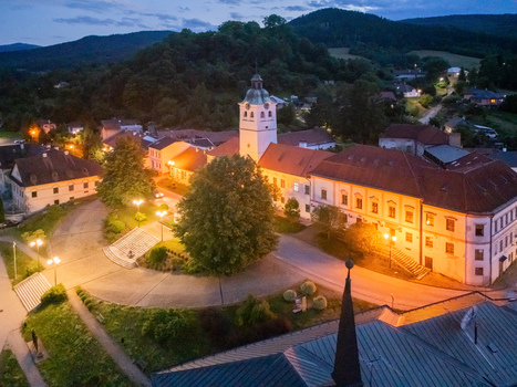 Aerial view of illuminated buildings casting warm glows against the twilight with a church steeple piercing the skyline Gelnica Kosice Region Slovakia. Aerial view of illuminated buildings casting warm glows against the twilight with a church steeple piercing the skyline Gelnica Kosice Region Slovakia.