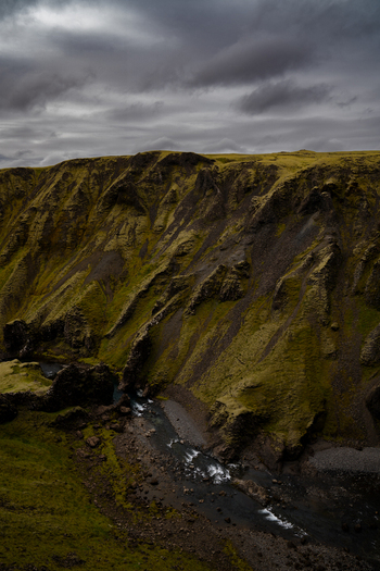 View of a dramatic ravine carved through mossy hills under a stormy sky water flowing through the landscape Skaftárhreppur Skaftárhreppur Iceland. View of a dramatic ravine carved through mossy hills under a stormy sky water flowing through the landscape Skaftárhreppur Skaftárhreppur Iceland.