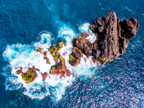 Aerial view of the rugged dark volcanic rocks kissed by frothy white waves creating a mesmerizing dance of power and serenity Pico Azores Portugal. Aerial view of the rugged dark volcanic rocks kissed by frothy white waves creating a mesmerizing dance of power and serenity Pico Azores Portugal.