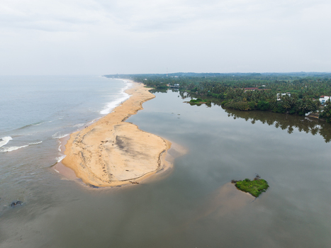 Aerial view of a narrow sandy beach separating the ocean from a calm lagoon with lush tropical vegetation in Galle Southern Province Sri Lanka. Aerial view of a narrow sandy beach separating the ocean from a calm lagoon with lush tropical vegetation in Galle Southern Province Sri Lanka.
