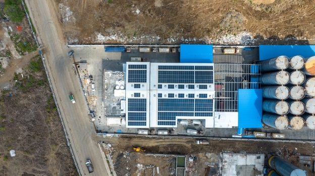 Aerial view of a warehouse facility featuring solar panels on the roof and large industrial storage silos situated in an industrial area in Bhiwandi Maharashtra India. Aerial view of a warehouse facility featuring solar panels on the roof and large industrial storage silos situated in an industrial area in Bhiwandi Maharashtra India.