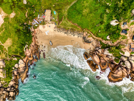 Aerial view of Praia do Gravata featuring a sandy beach turquoise ocean waves crashing against rocky cliffs and lush green vegetation in Florianopolis Santa Catarina Brazil. Aerial view of Praia do Gravata featuring a sandy beach turquoise ocean waves crashing against rocky cliffs and lush green vegetation in Florianopolis Santa Catarina Brazil.