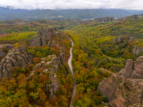 Aerial view of the dramatic Belogradchik Rocks surrounded by vibrant autumn forest and a winding road in Belogradchik Vidin Bulgaria. Aerial view of the dramatic Belogradchik Rocks surrounded by vibrant autumn forest and a winding road in Belogradchik Vidin Bulgaria.