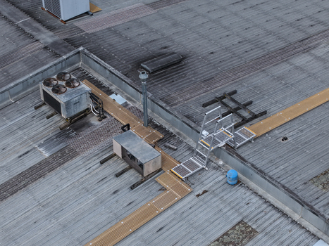 Aerial view of an industrial rooftop featuring HVAC units metal walkways and safety ladders on a corrugated metal surface in Melbourne VIC Australia.