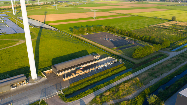 Aerial view of the Wabico BV industrial facility featuring a wind turbine solar panels and storage tanks surrounded by green fields in Waalwijk Noord Brabant Netherlands.