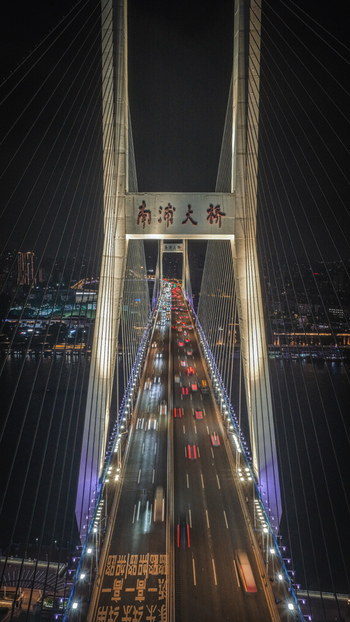 Aerial view of Nanpu Bridge at night with heavy traffic flow and illuminated cable stayed towers over the Huangpu River Shanghai Shanghai China.