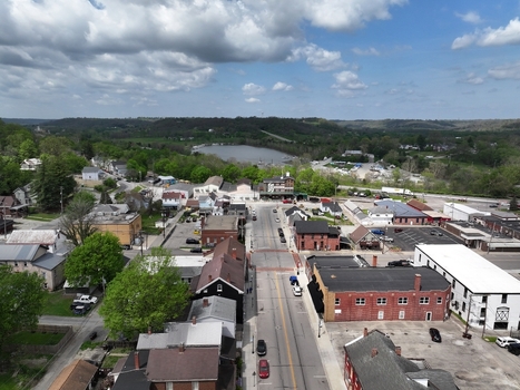 Aerial view of the historic downtown area with brick buildings residential streets and lush green trees under a cloudy sky in Aurora Indiana United States. Aerial view of the historic downtown area with brick buildings residential streets and lush green trees under a cloudy sky in Aurora Indiana United States.