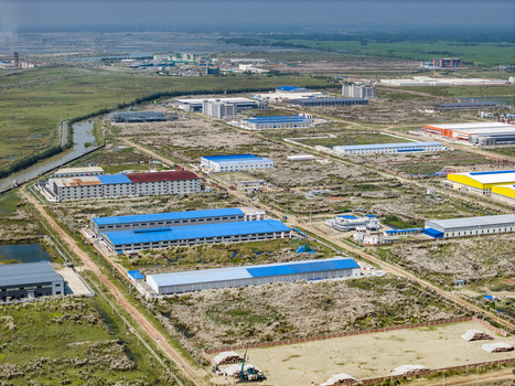 Aerial view of Mirsarai Economic Zone featuring modern industrial warehouses factory buildings with blue roofs and surrounding undeveloped land in Mirsarai Chittagong Division Bangladesh. Aerial view of Mirsarai Economic Zone featuring modern industrial warehouses factory buildings with blue roofs and surrounding undeveloped land in Mirsarai Chittagong Division Bangladesh.