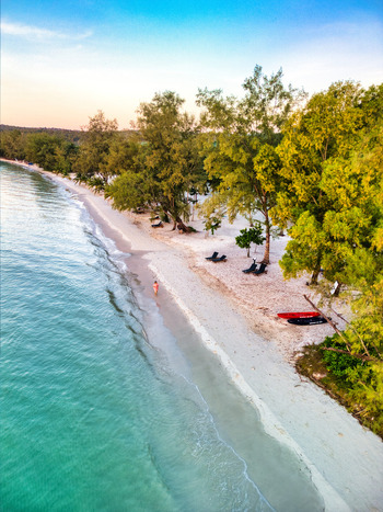 Aerial view of turquoise waters meet the pristine white sands fringed by verdant trees under a serene sky Preah Sihanouk Sihanoukville Cambodia.