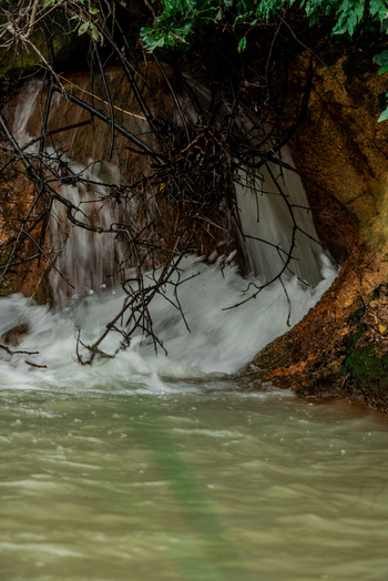 View of a small waterfall cascading over a rocky bank with tangled tree branches and roots hanging over the water in Jos North Plateau Nigeria. View of a small waterfall cascading over a rocky bank with tangled tree branches and roots hanging over the water in Jos North Plateau Nigeria.