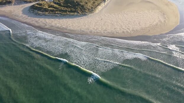 Aerial view of waves rolling onto the sandy beach Ireland.