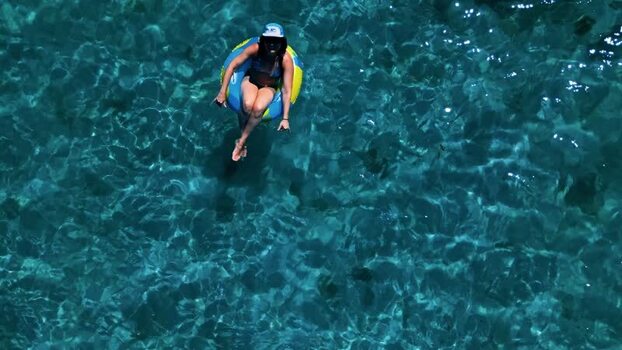 Aerial view of a woman floating on an inflatable ring in Guanaja Honduras. Aerial view of a woman floating on an inflatable ring in Guanaja Honduras.