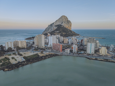 Aerial view of the Penon de Ifach rock formation rising above the coastal city of Calp with high rise buildings and the Mediterranean Sea Calp Valencian Community Spain. Aerial view of the Penon de Ifach rock formation rising above the coastal city of Calp with high rise buildings and the Mediterranean Sea Calp Valencian Community Spain.