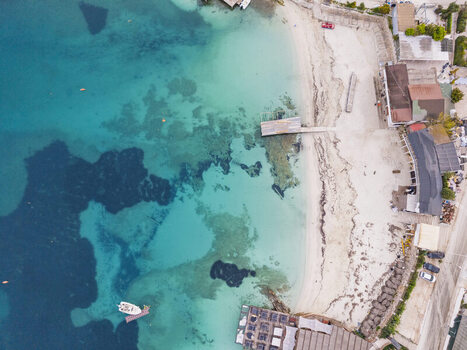 Aerial view of the beach with turquoise waters a wooden pier and coastal buildings in Ksamil Vlore County Albania. Aerial view of the beach with turquoise waters a wooden pier and coastal buildings in Ksamil Vlore County Albania.