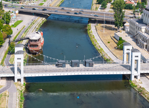Aerial view of the Art Bridge spanning the Vardar River with a decorative ship moored nearby and traffic on the adjacent road in Skopje Greater Skopje North Macedonia. Aerial view of the Art Bridge spanning the Vardar River with a decorative ship moored nearby and traffic on the adjacent road in Skopje Greater Skopje North Macedonia.