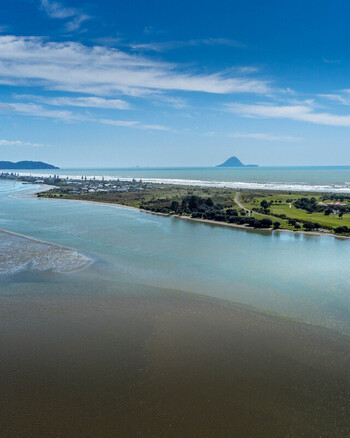 Aerial view of the coastal landscape at Ohope featuring the estuary sandy beach and calm ocean waters under a clear blue sky in Ohope Bay of Plenty Region New Zealand.
