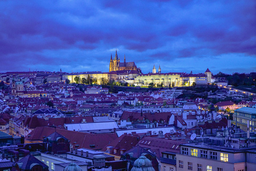 Aerial view of Prague Castle illuminated at twilight above the historic rooftops of the old town in Prague Prague Czechia. Aerial view of Prague Castle illuminated at twilight above the historic rooftops of the old town in Prague Prague Czechia.