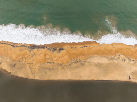 Aerial view of ocean waves crashing on a sandy beach strip separating the sea from a dark lagoon in Galle Southern Province Sri Lanka. Aerial view of ocean waves crashing on a sandy beach strip separating the sea from a dark lagoon in Galle Southern Province Sri Lanka.