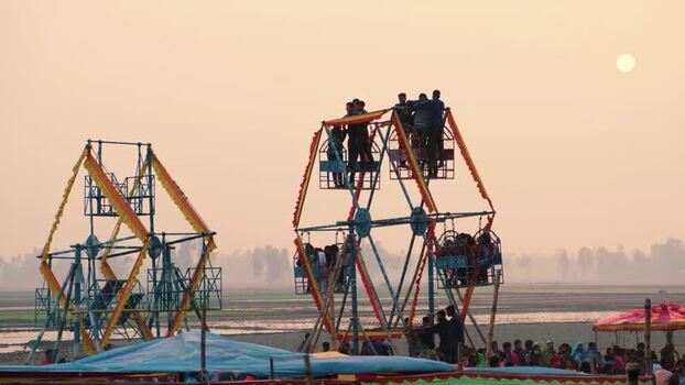 View of people riding a Ferris wheel at sunset in Bogura Bangladesh. View of people riding a Ferris wheel at sunset in Bogura Bangladesh.