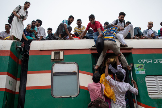 Dhaka Bangladesh 15 June 2018 View of crowded passengers sitting on the roof and climbing into the doors of a green and red train at Airport Railway Station. Dhaka Bangladesh 15 June 2018 View of crowded passengers sitting on the roof and climbing into the doors of a green and red train at Airport Railway Station.