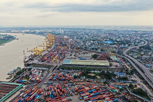 Aerial view of Chattogram Port with colorful shipping containers yellow gantry cranes and cargo ships along the Karnaphuli River in Chittagong Chittagong Division Bangladesh.