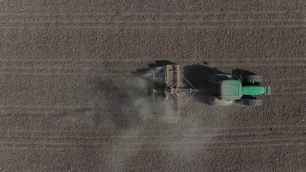 Aerial view of a green tractor plowing a dry field Portugal. Aerial view of a green tractor plowing a dry field Portugal.