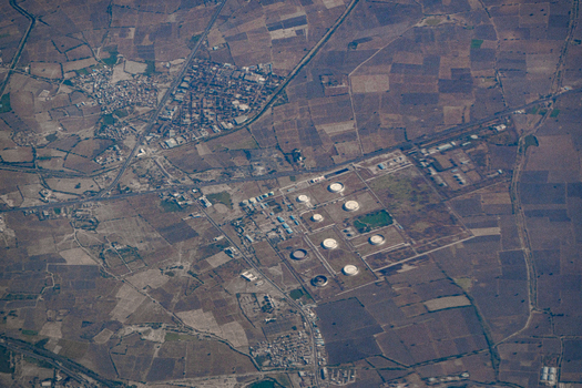 Aerial view of an industrial facility with circular storage tanks surrounded by a patchwork of agricultural fields and rural settlements India. Aerial view of an industrial facility with circular storage tanks surrounded by a patchwork of agricultural fields and rural settlements India.