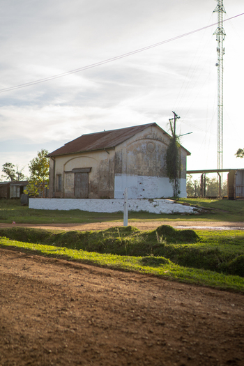 View of a historic weathered building with a rusty roof and white painted base situated near a dirt road in Guaviravi Corrientes Province Argentina.