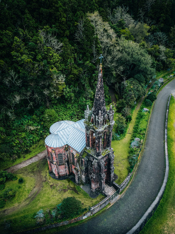 Aerial view of Ermida da Senhora das Vit&oacute;rias standing majestically amidst verdant foliage its dark stone contrasting with the silver roof Furnas Portugal.