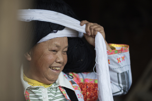 Gaoxing China 29 April 2026 View of a Long Horn Miao woman smiling while wrapping her traditional large white and black headdress. Gaoxing China 29 April 2026 View of a Long Horn Miao woman smiling while wrapping her traditional large white and black headdress.