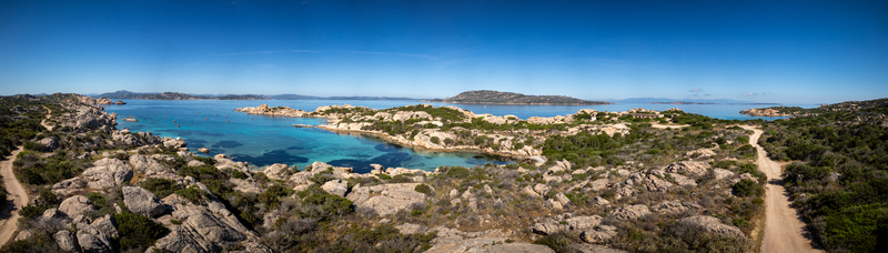 Aerial view of the rugged coastline of Punta Carlotto with turquoise waters granite rocks and Mediterranean vegetation under a clear blue sky in La Maddalena Sardinia Italy. Aerial view of the rugged coastline of Punta Carlotto with turquoise waters granite rocks and Mediterranean vegetation under a clear blue sky in La Maddalena Sardinia Italy.
