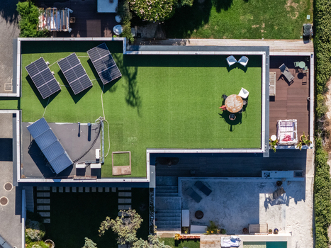 Aerial view of a modern house rooftop featuring solar panels artificial grass and a patio area with furniture in Cascais Lisboa Portugal. Aerial view of a modern house rooftop featuring solar panels artificial grass and a patio area with furniture in Cascais Lisboa Portugal.
