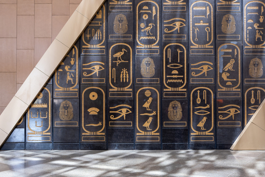 Giza Egypt 16 May 2026 View of Grand Egyptian Museum featuring golden hieroglyphics and cartouches on a black stone wall with modern architectural elements.