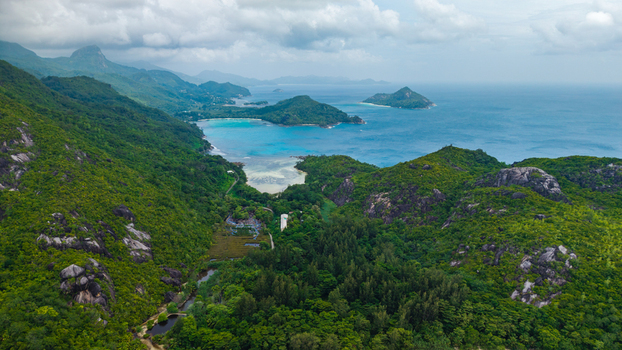 Aerial view of the lush green hills and rocky coastline of Cap Ternay overlooking the turquoise waters of the bay in Cap Ternay Port Glaud Seychelles. Aerial view of the lush green hills and rocky coastline of Cap Ternay overlooking the turquoise waters of the bay in Cap Ternay Port Glaud Seychelles.