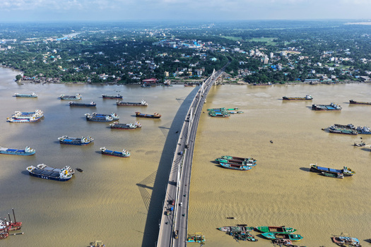 Aerial view of the Shah Amanat Bridge spanning the Karnaphuli River with numerous cargo ships navigating the waterway in Chattogram Chittagong Division Bangladesh.