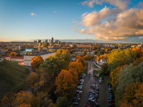 Aerial view of autumn hues paint the trees surrounding the cityscape contrasting with the modern skyline beyond the Neris River Vilnius Lithuania. Aerial view of autumn hues paint the trees surrounding the cityscape contrasting with the modern skyline beyond the Neris River Vilnius Lithuania.