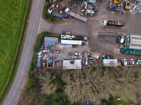 Aerial view of a bustling scrapyard where hues of rust and silver intermingle with the surrounding greenery and the stark asphalt of Common Road Stafford England United Kingdom. Aerial view of a bustling scrapyard where hues of rust and silver intermingle with the surrounding greenery and the stark asphalt of Common Road Stafford England United Kingdom.