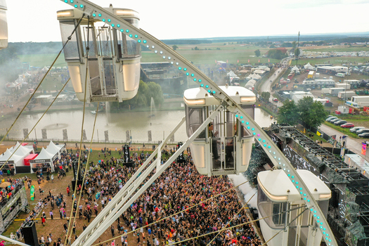 Herzogenaurach Germany 24 July 2025 Aerial view of Open Beatz Festival with a large crowd gathered near the main stage and Ferris wheel gondolas in the foreground.