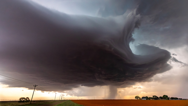 View of a massive supercell storm cloud with a rotating funnel over a rural field with power lines in Oklahoma City Oklahoma United States.