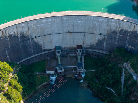 Aerial view of the Barrage de Rossens concrete dam wall with turquoise water and lush green forest in Pont la Ville Fribourg Switzerland.