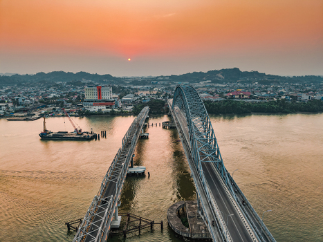 Aerial view of Jembatan Mahakam I spanning the Mahakam River at sunset with the city skyline and a barge in the water in Kecamatan Samarinda Seberang Kalimantan Timur Indonesia. Aerial view of Jembatan Mahakam I spanning the Mahakam River at sunset with the city skyline and a barge in the water in Kecamatan Samarinda Seberang Kalimantan Timur Indonesia.
