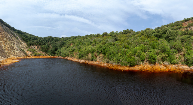 Aerial view of the Laghetto delle conche known as the Blood Lake with its deep red water surrounded by rocky cliffs and lush green vegetation in Rio Marina Toscana Italy.