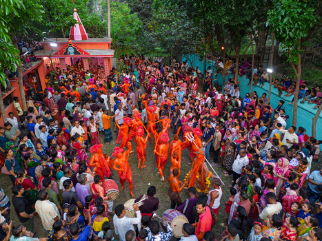 Munshiganj Bangladesh 13 April 2026 Aerial view of vibrant orange clad performers captivating a dense crowd near a distinct pink roofed temple amidst verdant foliage.
