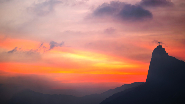 View of the silhouette of Christ the Redeemer statue on Corcovado mountain against a vibrant sunset sky in Rio de Janeiro Rio de Janeiro Brazil.