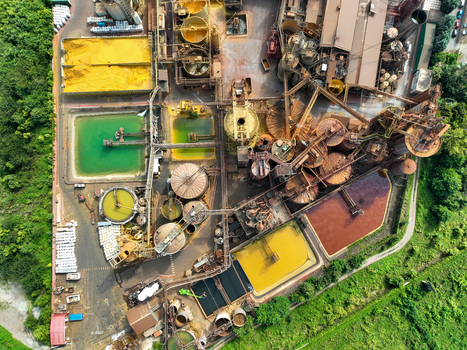 Aerial view of an industrial facility with large storage tanks complex piping systems and colorful settling ponds surrounded by green trees in Turin Piedmont Italy. Aerial view of an industrial facility with large storage tanks complex piping systems and colorful settling ponds surrounded by green trees in Turin Piedmont Italy.