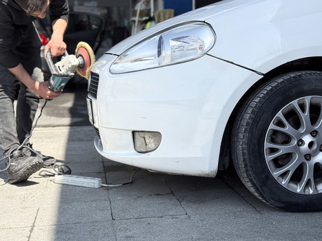 View of a man using a rotary polisher to buff the front bumper of a white car at a detailing shop in Avcilar Istanbul Turkiye. View of a man using a rotary polisher to buff the front bumper of a white car at a detailing shop in Avcilar Istanbul Turkiye.